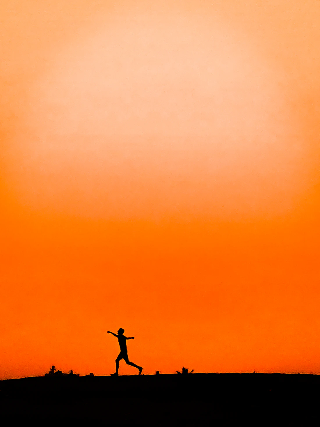 Runner silhouetted against an orange sky against a blue sky